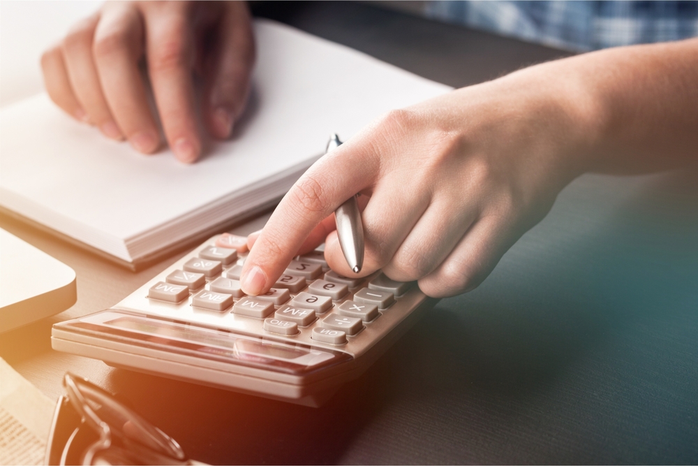 calculating labor burden on calculator with pen in hand